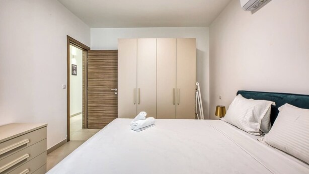 A hotel room with a bed, a wardrobe, a desk, and a wall-mounted air conditioner. - Beautiful, fully equipped 3BR in Sliema w/Balcony (Tas-Sliema)