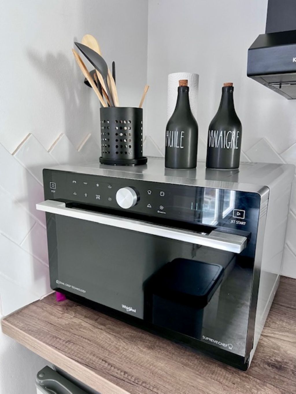 Una cocina con horno empotrado, panel de control y campana extractora de acero inoxidable.