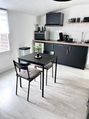 Eine moderne Küche mit Esstisch und Stühlen, einem eingebauten Backofen und einer Kaffeemaschine.
