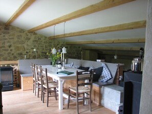 Ein Essbereich mit Steinsandsteinwand, Holzbalken, einem mit Kerzen gedeckten Tisch und einem Fernseher.