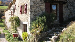 A stone building with a door and windows, surrounded by vegetation and a path. - Holiday Home in Small Hamlet Surrounded by Fields and Mountains (Bouvières)