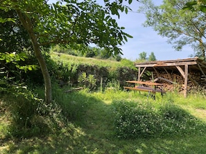 A rustic outdoor setting with a wooden structure, possibly a shed, surrounded by lush greenery and a stone wall. - Holiday Home in Small Hamlet Surrounded by Fields and Mountains (Bouvières)