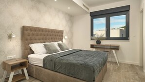 Ein Schlafzimmer mit einem großen Bett, Nachttischen, einem Schreibtisch und einem Fenster mit Blick.