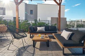 A rooftop terrace with a wooden table, two black sofas, and a black chair. - Luxury villa Natali with pool, terrace and sea view (Podstrana - Sita)