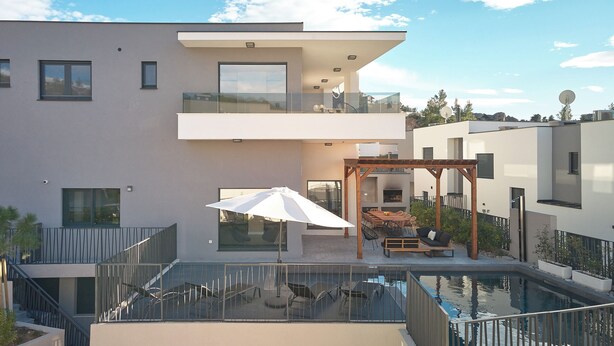 Ein modernes, zweistöckiges Gebäude mit Pool auf dem Dach, Außenbereich und einer Pergola.