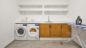 Ein Waschraum mit zwei Waschmaschinen, einem Waschbecken, Holzausbau und einem Wäscheständer.