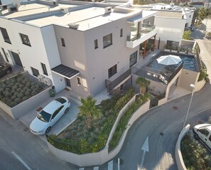 A modern multi-story building with balconies, a rooftop garden, and a white car parked in front. - Luxury villa Natali with pool, terrace and sea view (Podstrana - Sita)