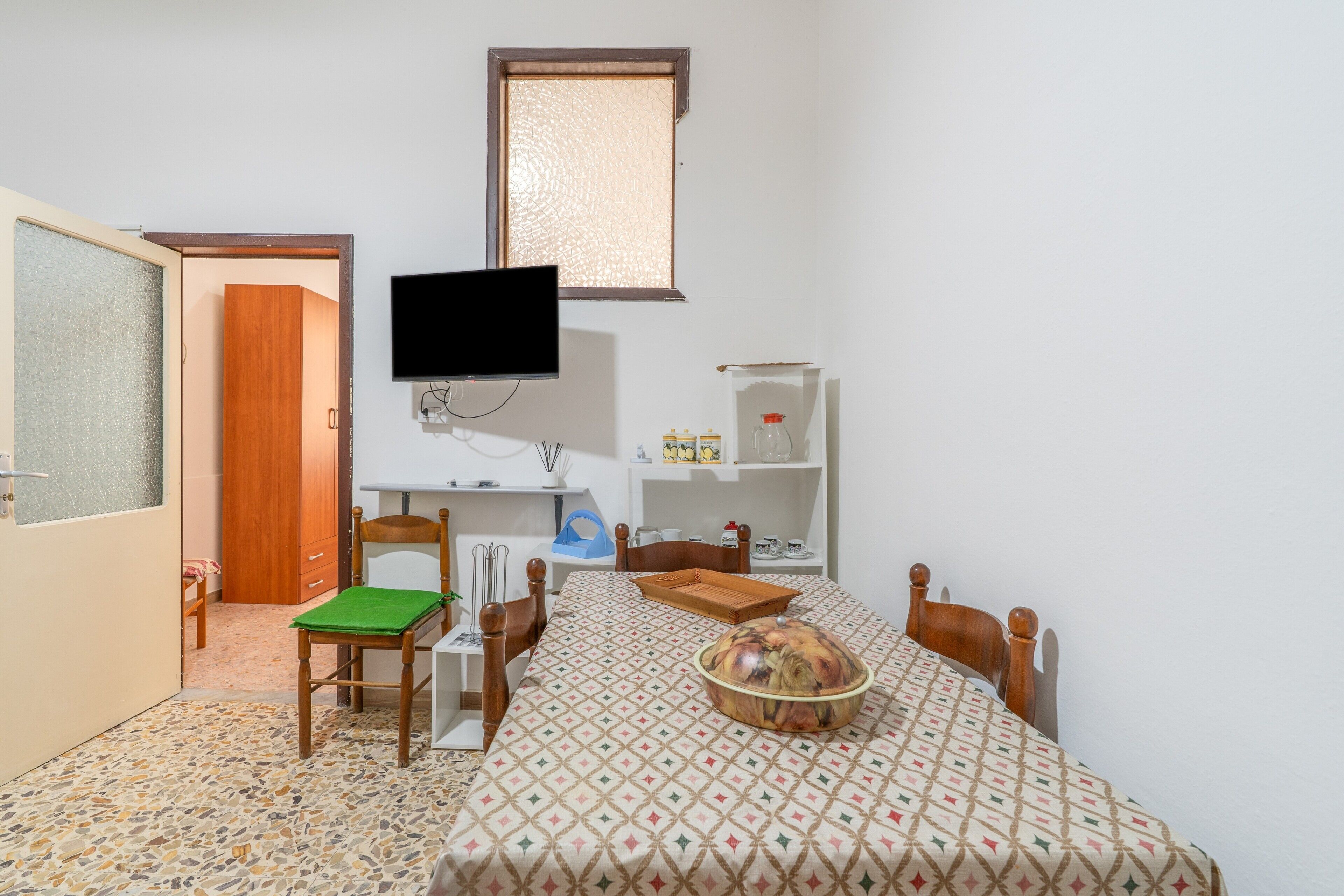 Ein Zimmer mit Esstisch, Stühlen, Fernseher und Fenster.