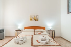 Ein Hotelzimmer mit einem Bett, zwei Nachttischlampen, einer Heizung und einem Bild an der Wand.