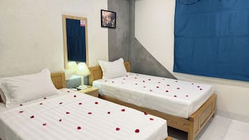 A hotel room with two beds, a nightstand, a lamp, a mirror, and a blue curtain.