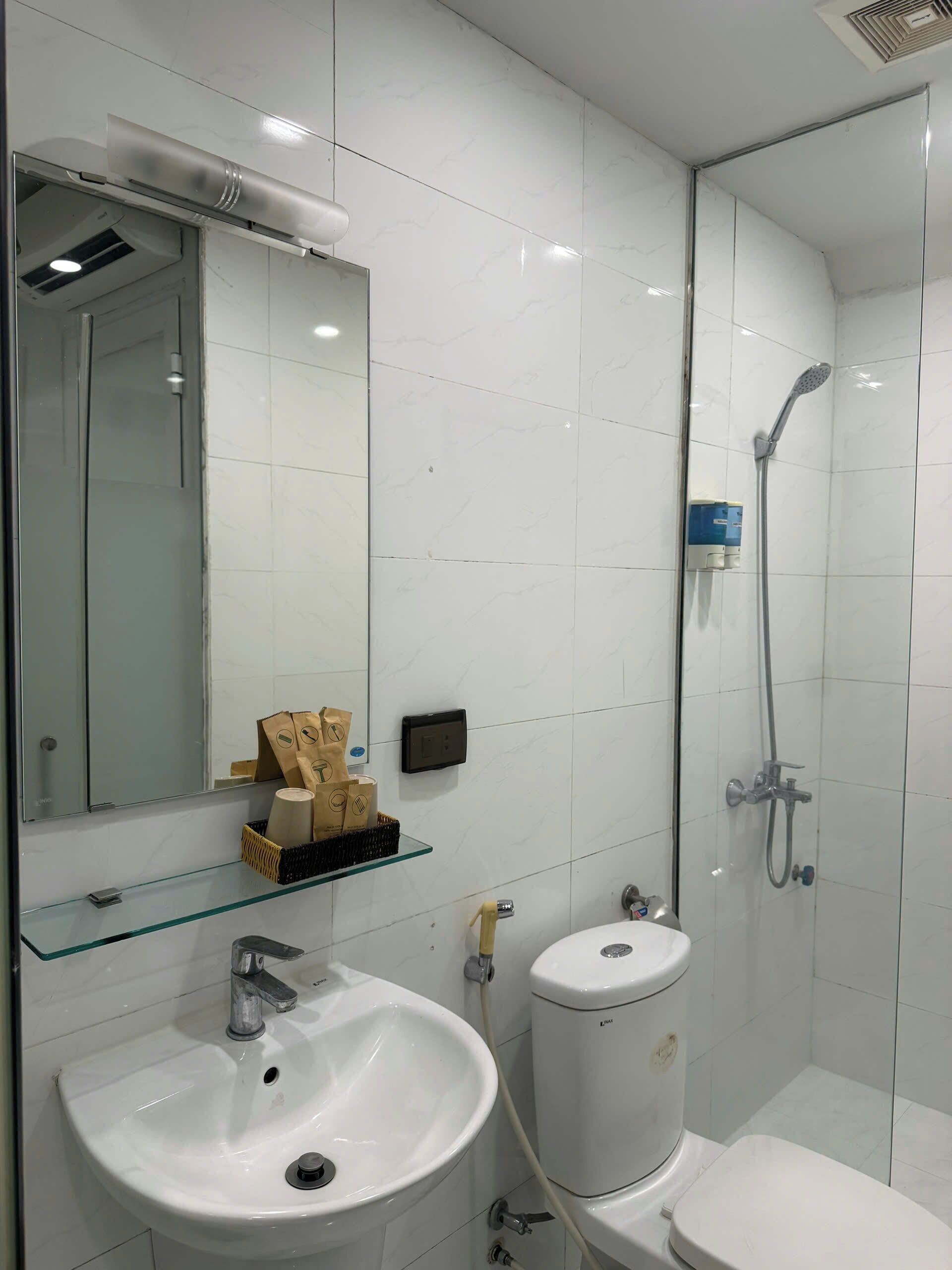 Un baño moderno con cabina de ducha de vidrio, un lavabo blanco y un inodoro.
