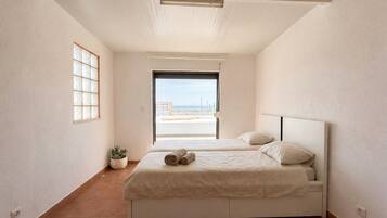 Une chambre à coucher avec un lit, une plante en pot et une vue sur la mer.