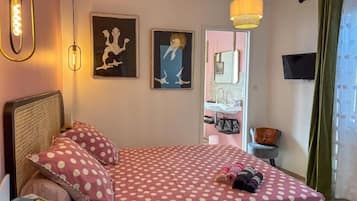 A bedroom with a bed, a bedside table, a lamp, and artwork on the wall.