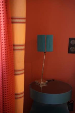 Una lámpara sobre una mesa redonda frente a una pared roja.