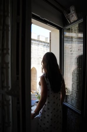 Una persona de pie junto a una ventana con vistas a un edificio.