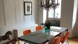 Ruokailutila, jossa on pöytä, tuoleja, kattokruunu ja keinutuolihevonen.