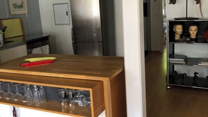 Moderni keittiö, jossa on puinen keittiösaareke, ruostumattomasta teräksestä valmistettu jääkaappi ja lasinen vitriinikaappi.