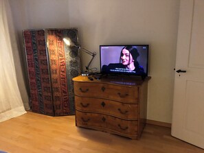A television on a wooden dresser with a patterned tapestry in the background. - The historic town of Laupen near Bern—Top-Notch Apartment on the 1st Floor (Laupen)