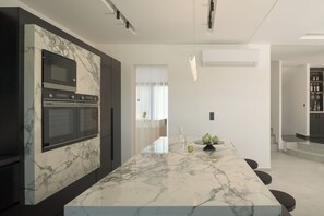 A modern kitchen with a marble countertop, built-in appliances, and a central island. - Ariselia Villa, Grand Spaces, Wellness & Play (Retymno)