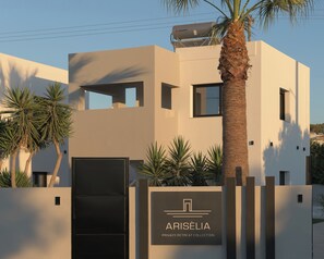 A modern building with a minimalist design, featuring a prominent palm tree and a sign that reads 'ARISELIA PRIVATE RETREAT COLLECTION.' - Ariselia Villa, Grand Spaces, Wellness & Play (Retymno)
