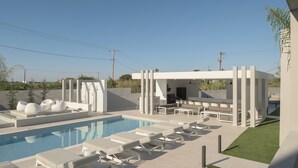 A modern outdoor pool area with lounge chairs and a barbecue setup. - Ariselia Villa, Grand Spaces, Wellness & Play (Retymno)