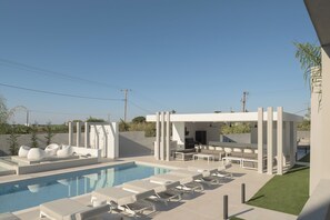 Ein moderner Poolbereich im Freien mit Liegestühlen und einer Grillmöglichkeit.