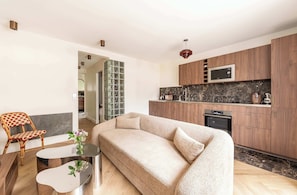 Ein stilvolles Wohnzimmer mit einem beigefarbenen Sofa, einem Glastisch und einem Korbstuhl.