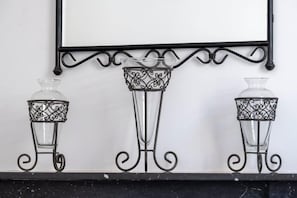 Drei Glasvasen mit Metallständern auf einem Regal vor einer weißen Wand.