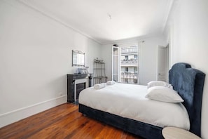 Ein Schlafzimmer mit einem großen Bett, einem Schminktisch, einem Spiegel und Blick auf einen Balkon.