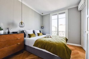 A bedroom with a bed, bedside tables, a dresser, and a window with a view. - Chic Parisian 1BR Flat near Montparnasse (Paris)