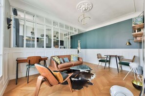 Een moderne woonkamer met een bank, stoelen, een salontafel en een eethoek met een tafel en stoelen.