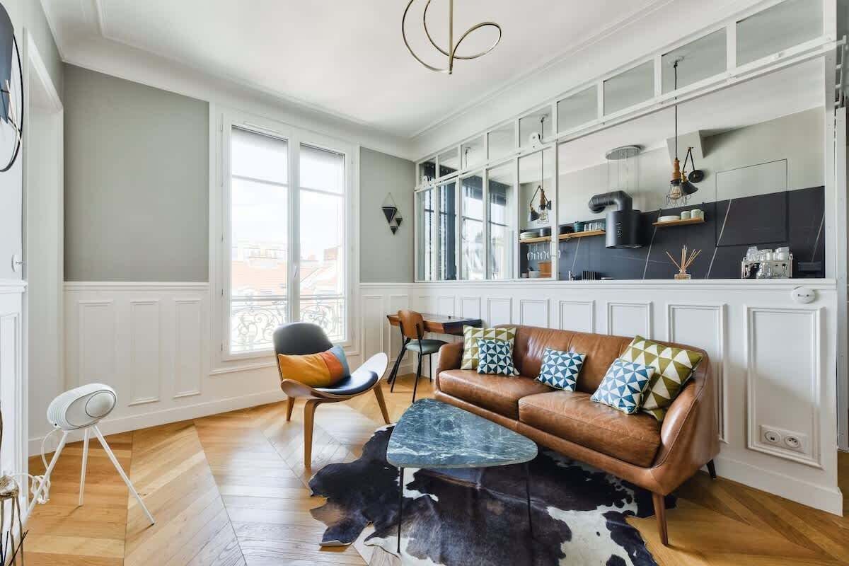 A modern living room with a leather sofa, a coffee table, and a dining area with chairs.