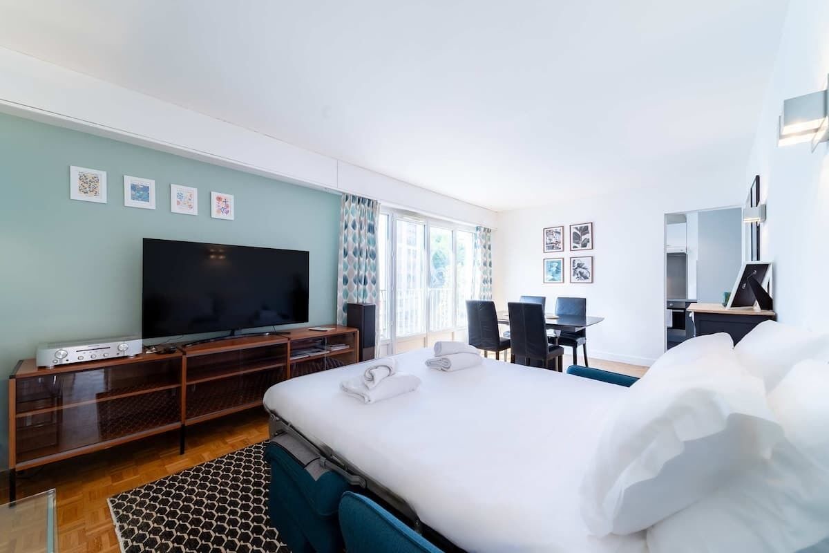 A hotel room with a bed, a TV, a desk, and a chair.