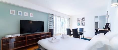 A hotel room with a bed, a TV, a desk, and a chair.