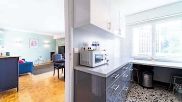 Een moderne keuken met een magnetron, een prullenbak en een raam.