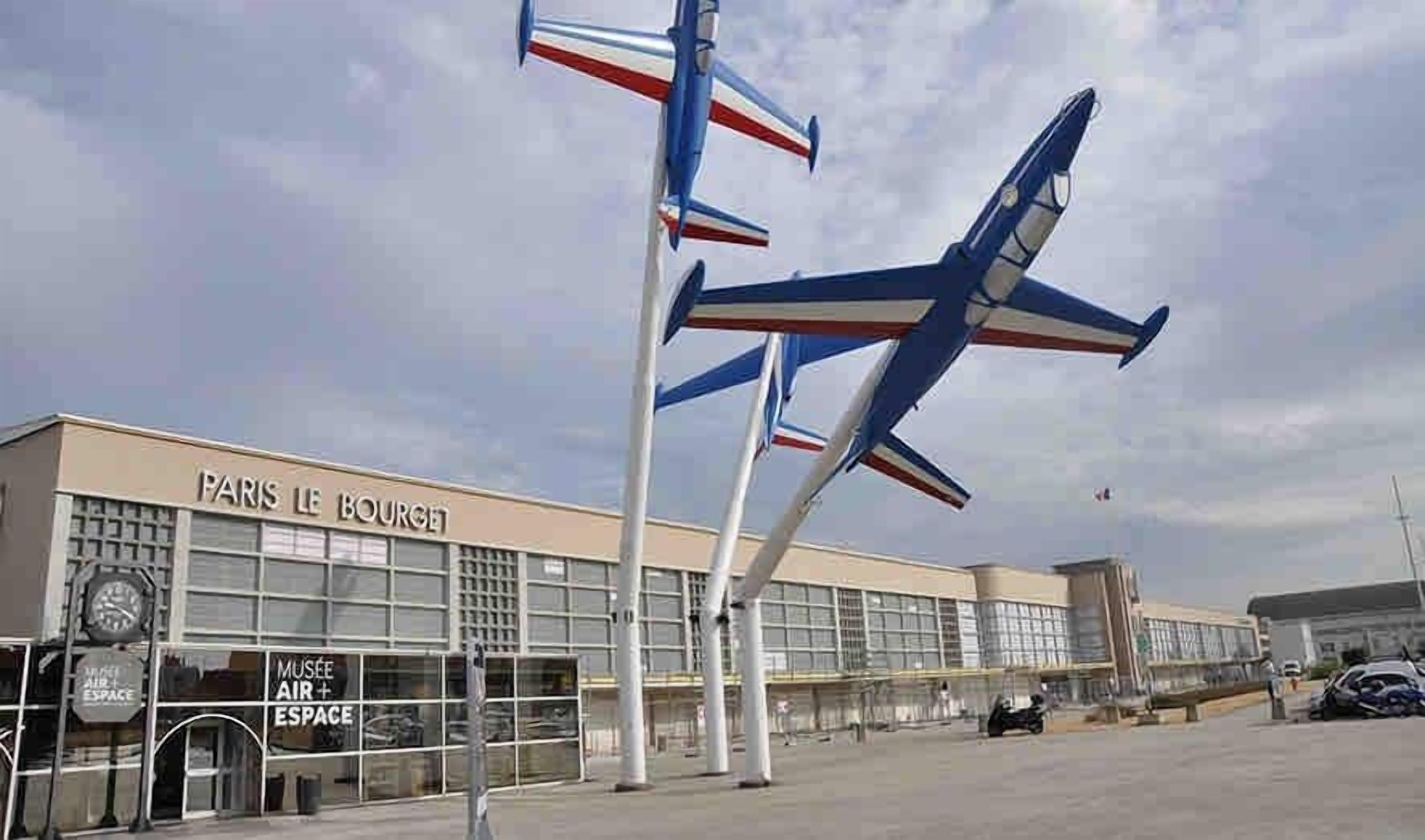 A building with a sign reading 'PARIS LE BOURGET' and a large airplane sculpture in front.