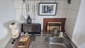 A kitchen with a toaster, a coffee maker, a sink, and a tray with condiments. - Studio Under the Rooftops - Sacre-Coeur View (Paris)