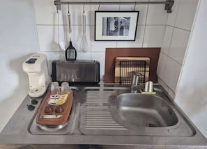 Eine Küche mit Toaster, Kaffeemaschine, Spüle und einer Ablage mit Gewürzen.