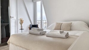 A modern bedroom with a large bed, two pillows, and two folded towels. - Studio Under the Rooftops - Sacre-Coeur View (Paris)
