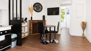 Una cocina moderna con estufa negra, un comedor con mesa y sillas redondas, un reloj negro en la pared y una chimenea.