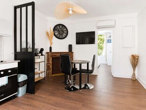 A modern kitchen with a black stove, a dining area with a round table and chairs, a black clock on the wall, and a fireplace. - Séjour idéal climatisé - Paris, CDG - Parking (Le Bourget)