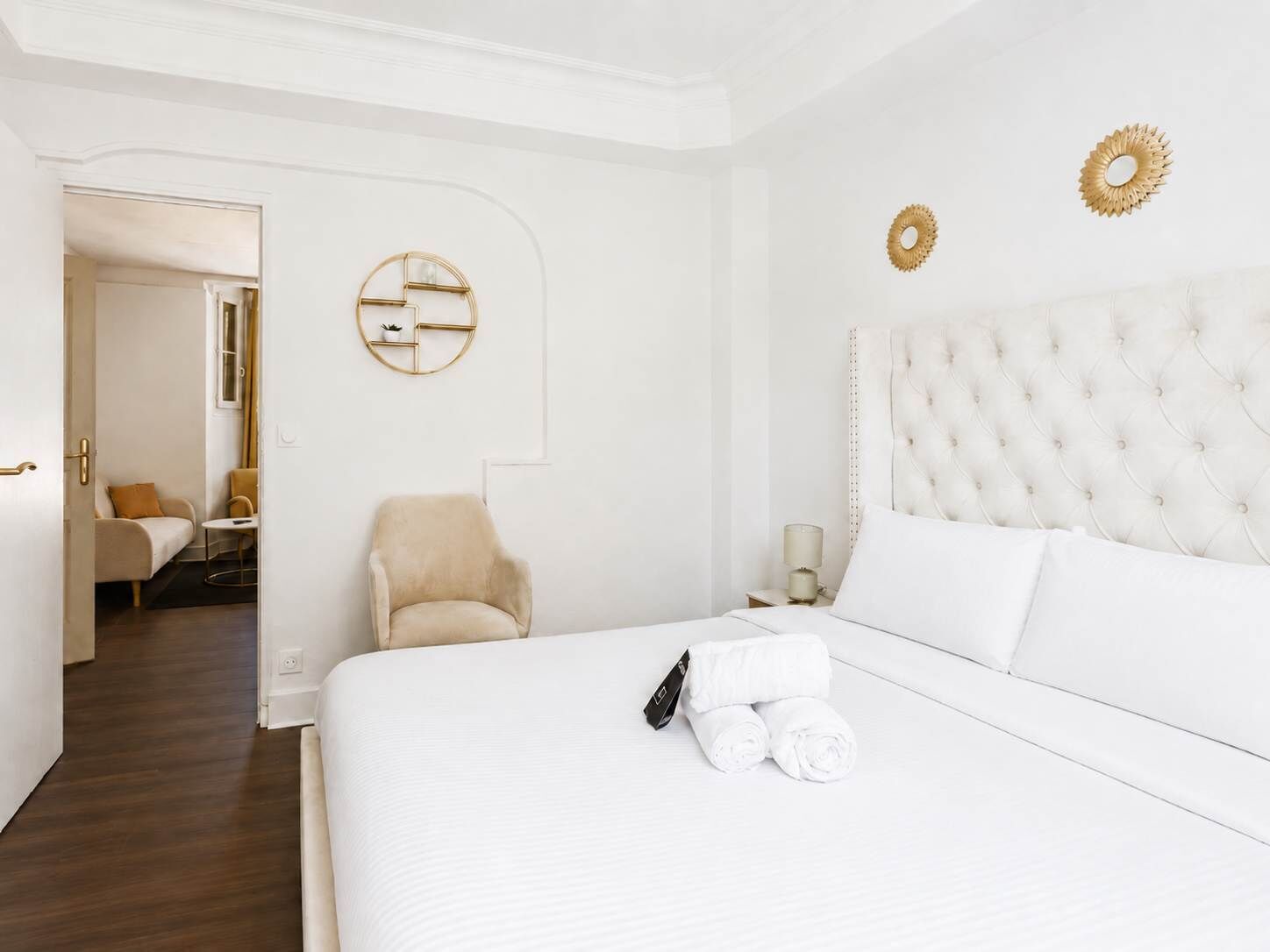 A hotel room with a large bed, a chair, a nightstand, and a wall-mounted decorative piece.