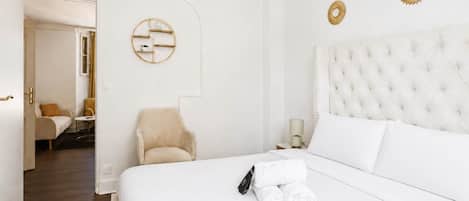 A hotel room with a large bed, a chair, a nightstand, and a wall-mounted decorative piece.