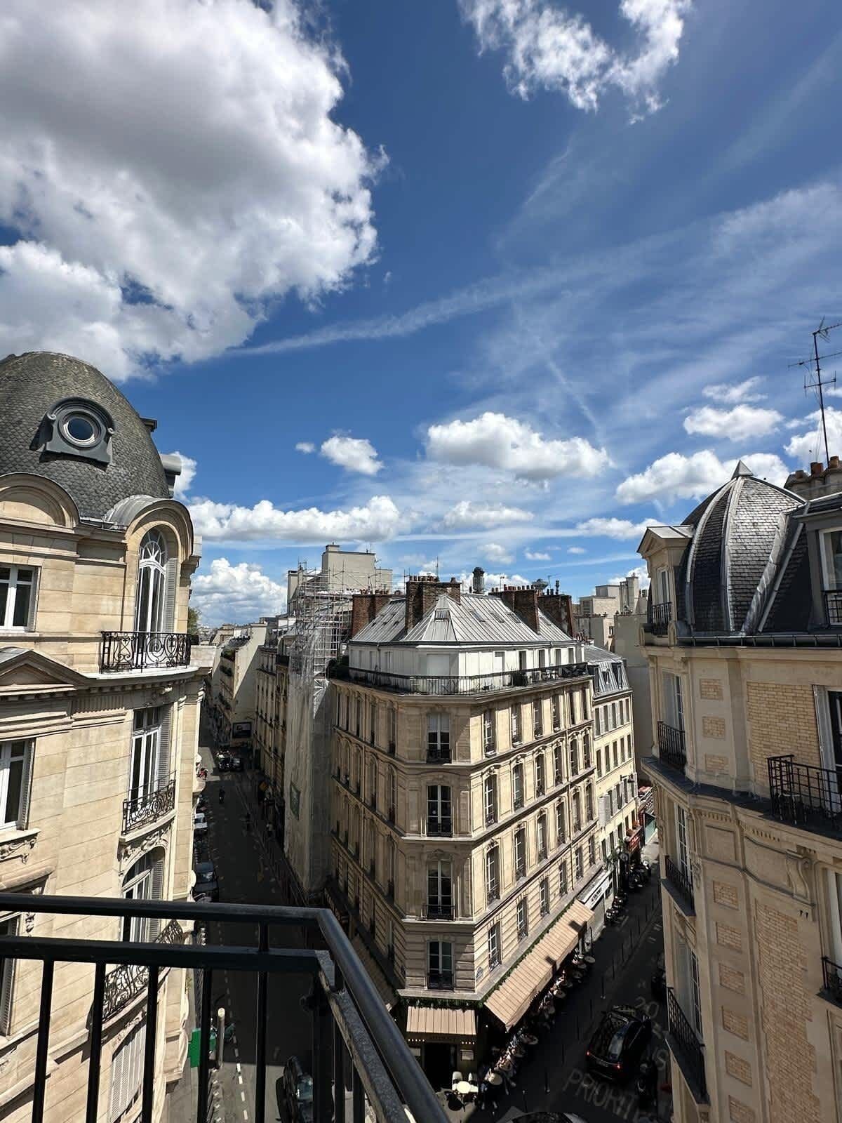 Straßenansicht mit Gebäuden, darunter ein Gebäude mit einer Kuppel und ein Gebäude mit einem Balkon.