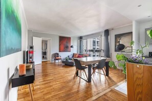A spacious living area with a dining table, a sofa, and a large window. - Spacious fully equipped 1-bedroom - Mobility lease (Paris)