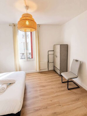 Ein Hotelzimmer mit einem Bett, einem Sessel, einem Kleiderschrank und einer Pendelleuchte.