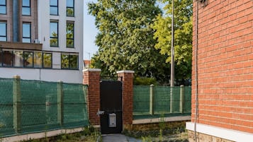 A pathway leading to a building with a brick facade and a green fence.