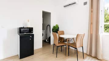 A compact living space with a kitchenette, a dining area with a round table and chairs, and a window with curtains.