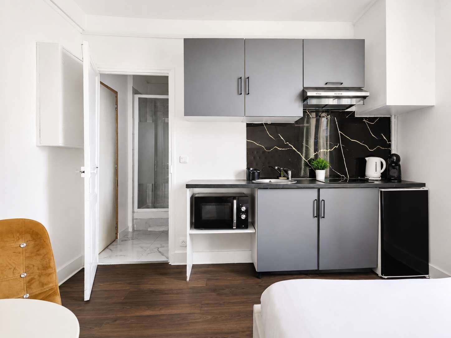 A compact kitchen with grey cabinets, a microwave, a coffee maker, and a small countertop.