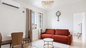 Ett modernt vardagsrum med en soffa, fåtöljer, ett litet bord och en hängande lampa.